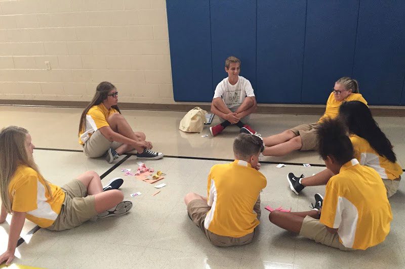 teens sitting on gym floor in a circle