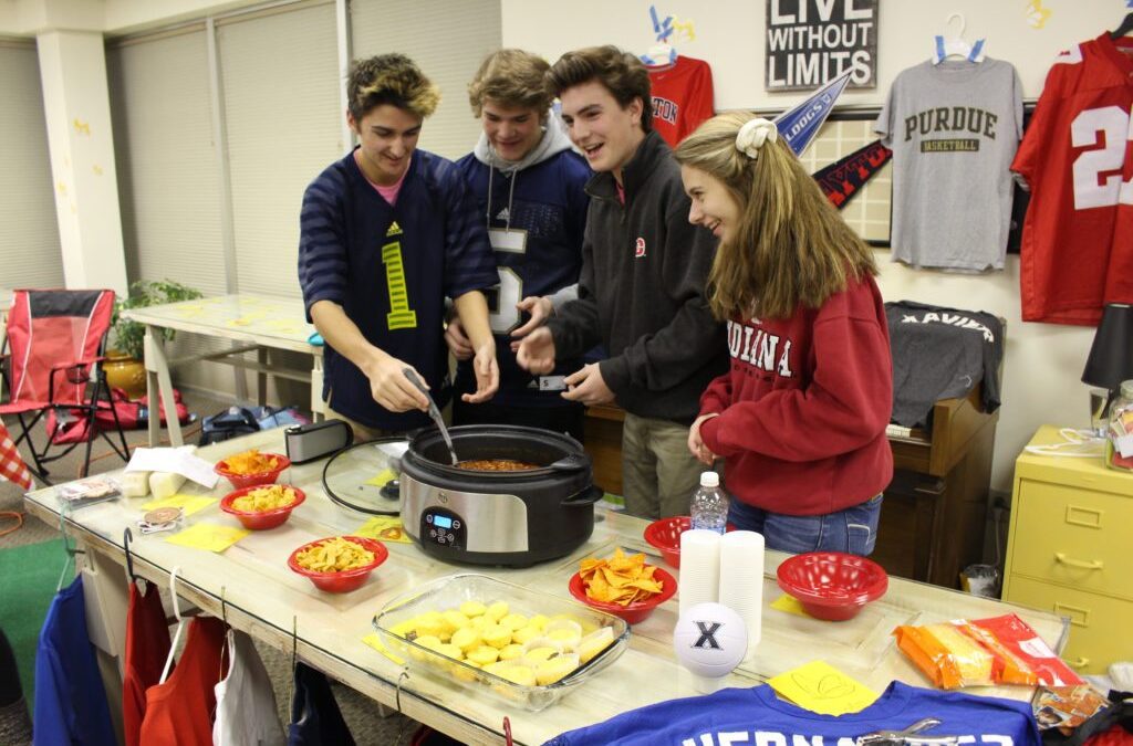 3 teen-aged boys and 1 teen-aged girl standing around an instant pot of chili and smiling