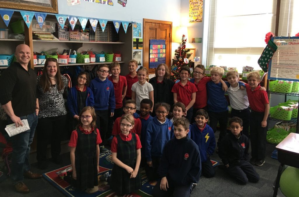 grade school class posing for picture in classroom with adult male teacher and young woman with Down syndrome