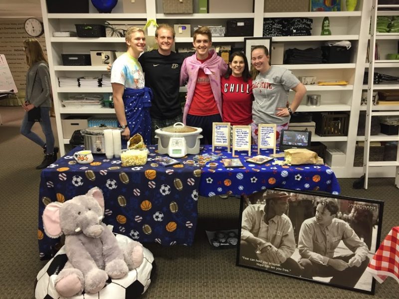 junior board standing behind a table with chili and other food items