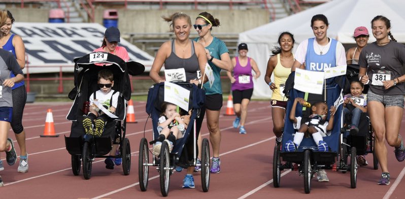 5k participants mid-race on a track and pushing kids in strollers