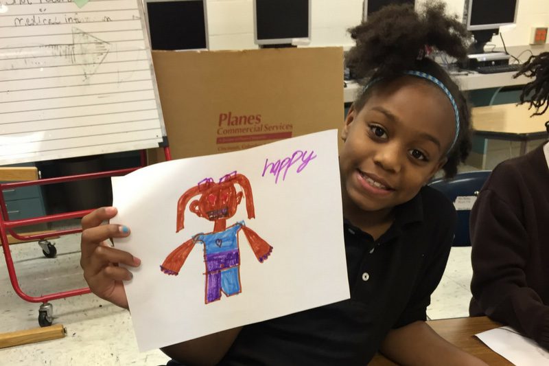 Young and happy African American girl dressed in school uniform and holding a picture she drew