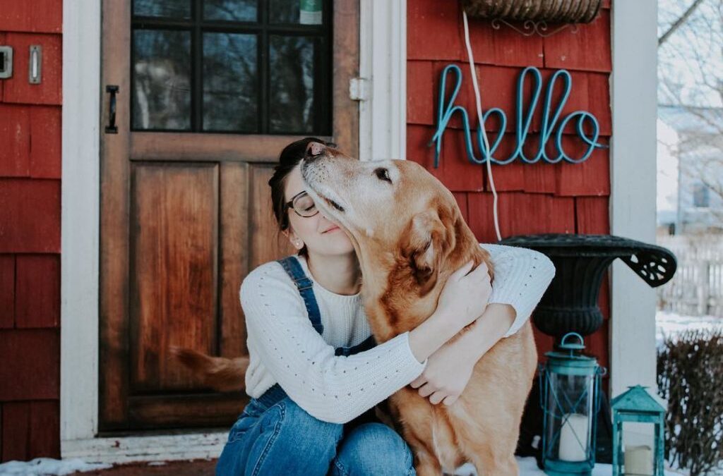 Dark haired woman hugging her golden retriever dog.