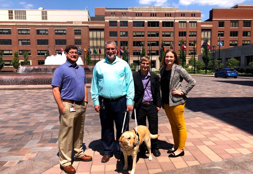 Mark Dresen with three adults and a service dog posing outside for a picture