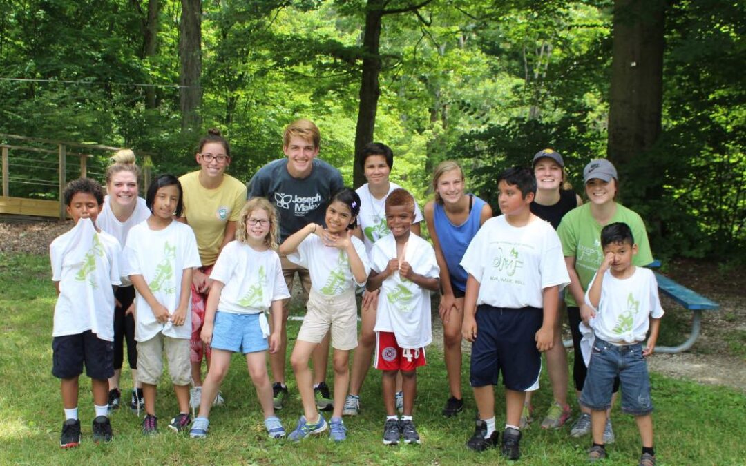 Group of volunteers smiling for a photo with young children outside