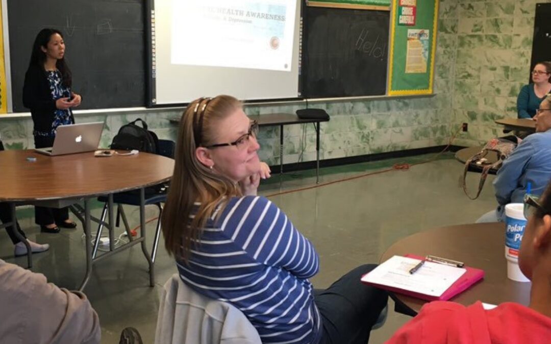 Classroom with adults listening to a doctor speak.