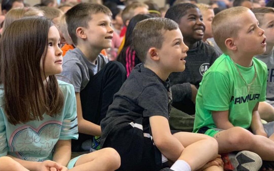 close up image of group of boys and girls smiling and intrigued by what they are looking at