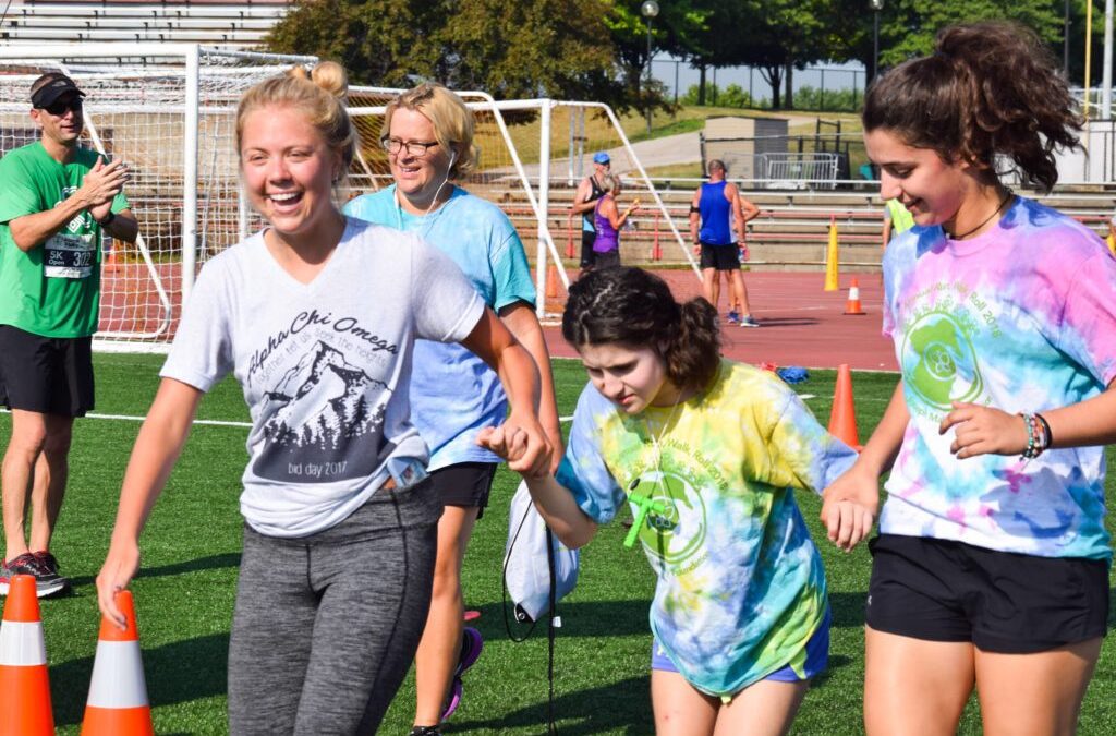 Teenagers helping a younger child at a Run, Walk, Roll event.