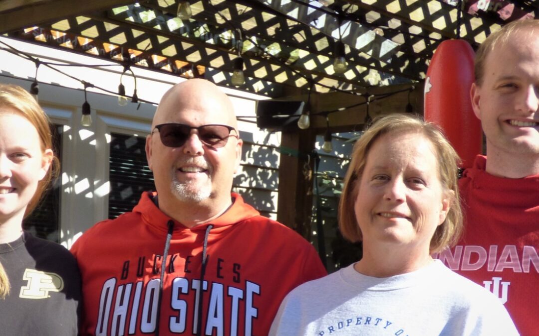 Tom Spreacker posing with his family and smiling at the camera.