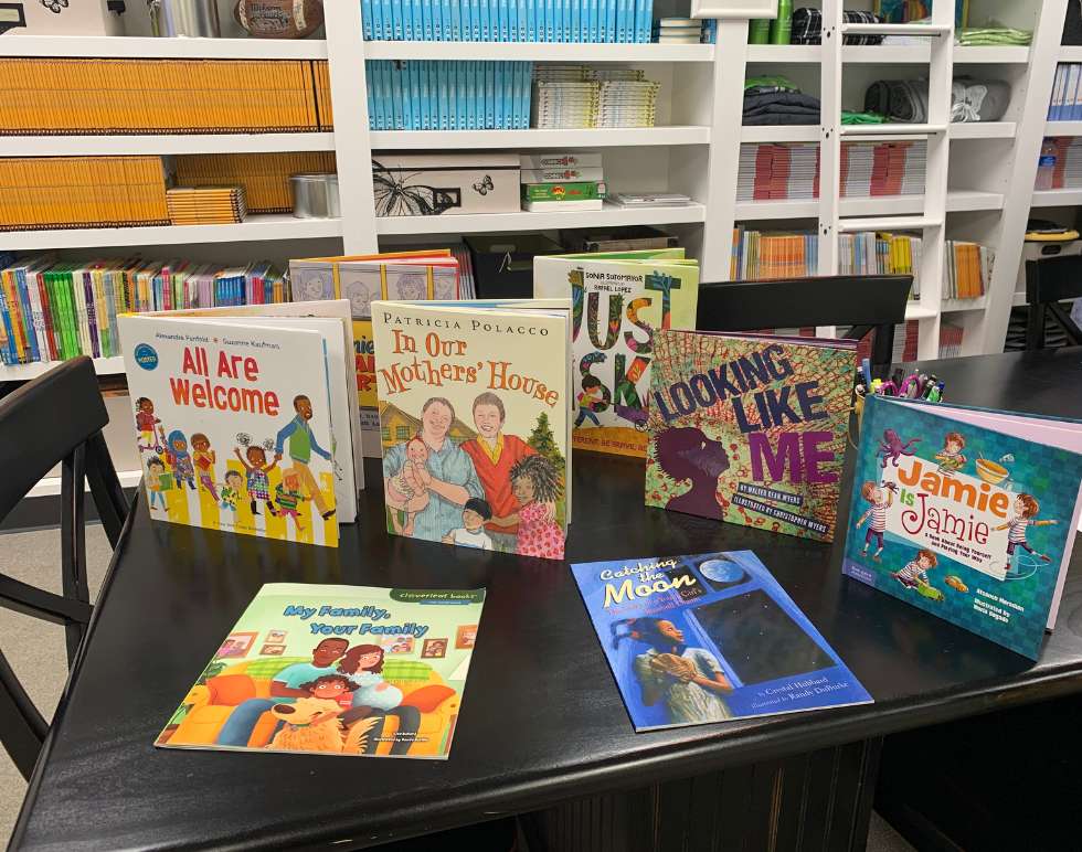 Children's picture books arranged on table, with colorful bookcase in background.